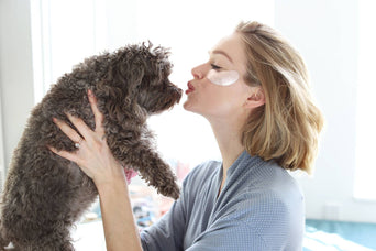 woman kissing a dog on the nose, with smear of product under her eyes