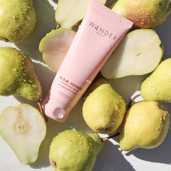 A tube of B.O.M. Voyage Cleansing Balm from Wander Beauty in between a few pears